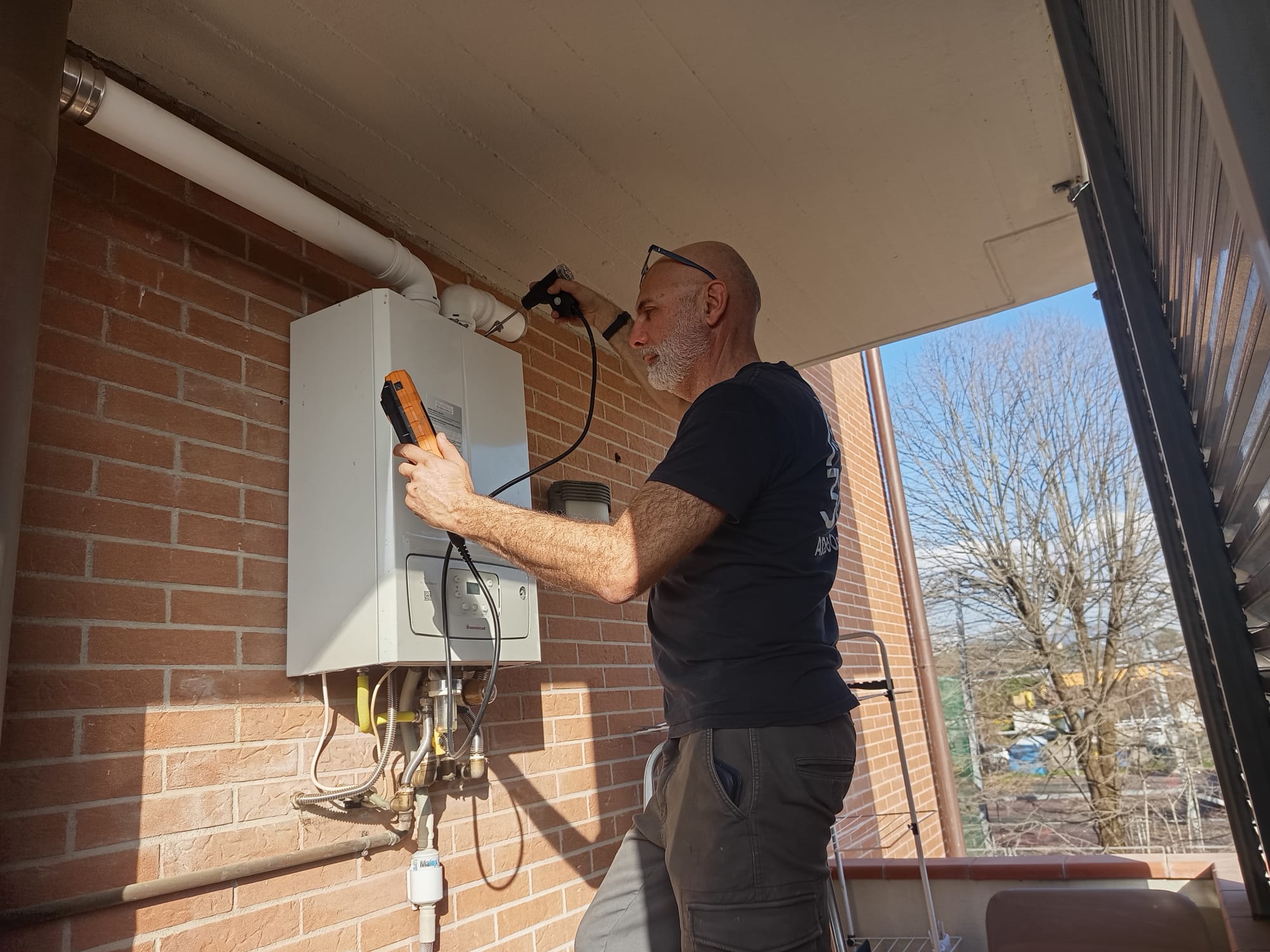 Tecnico ADL 360 srl durante controllo della combustione e verifica dei fumi su caldaia Immergas installata a Firenze.